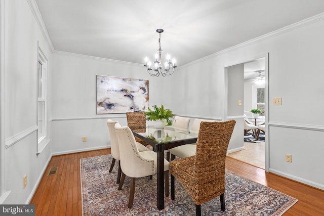 dining area featuring baseboards, ornamental molding, wood-type flooring, and a notable chandelier