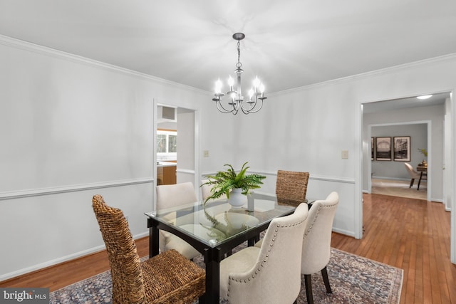 dining area with light wood finished floors, baseboards, a chandelier, and ornamental molding