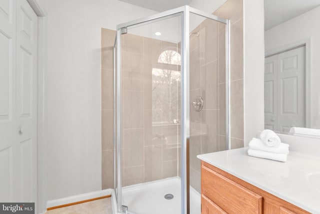 bathroom with a closet, a shower stall, and vanity