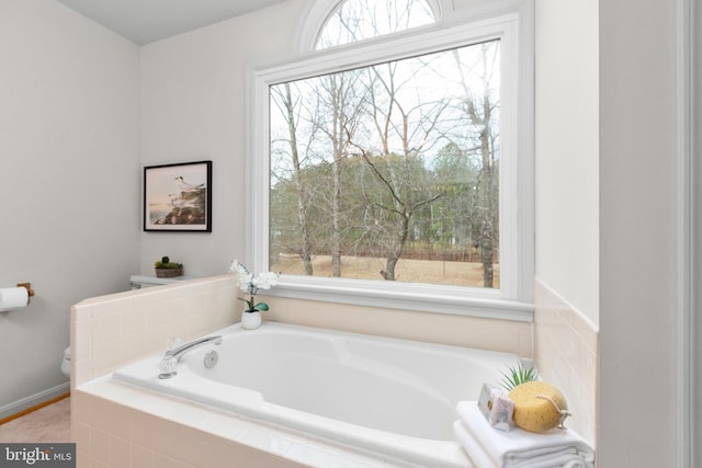 bathroom featuring toilet, a garden tub, and a wealth of natural light