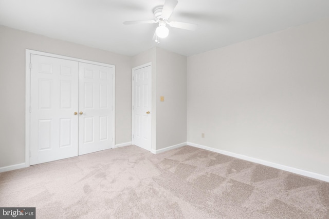 unfurnished bedroom featuring a closet, carpet, a ceiling fan, and baseboards