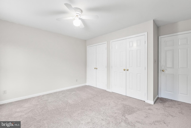 unfurnished bedroom with carpet floors, ceiling fan, baseboards, and multiple closets