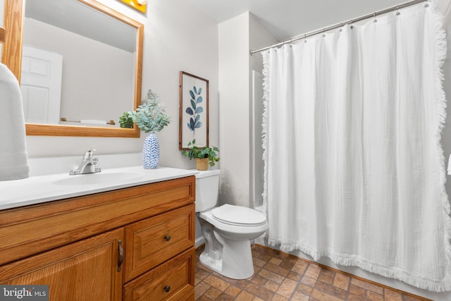 bathroom with curtained shower, vanity, and toilet