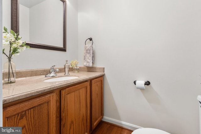 bathroom featuring baseboards, vanity, toilet, and wood finished floors