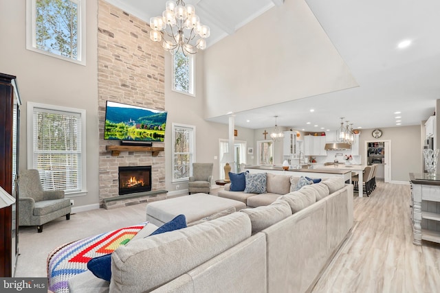 living room with baseboards, light wood finished floors, recessed lighting, a stone fireplace, and a notable chandelier