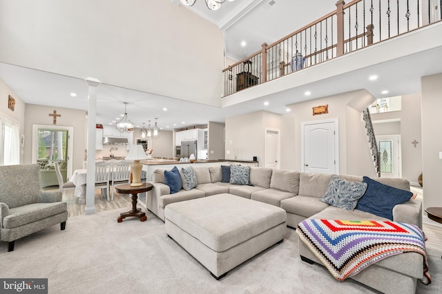 living area with wood finished floors, ornate columns, recessed lighting, a towering ceiling, and a notable chandelier