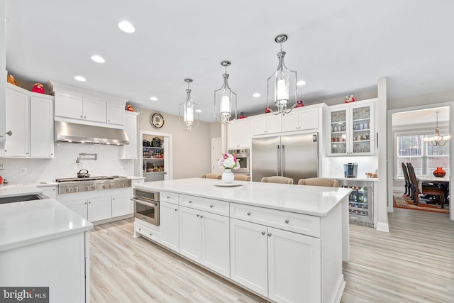 kitchen with white cabinets, appliances with stainless steel finishes, under cabinet range hood, and a center island