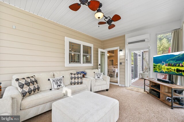 living room featuring carpet flooring, a ceiling fan, wood walls, and a wall mounted air conditioner