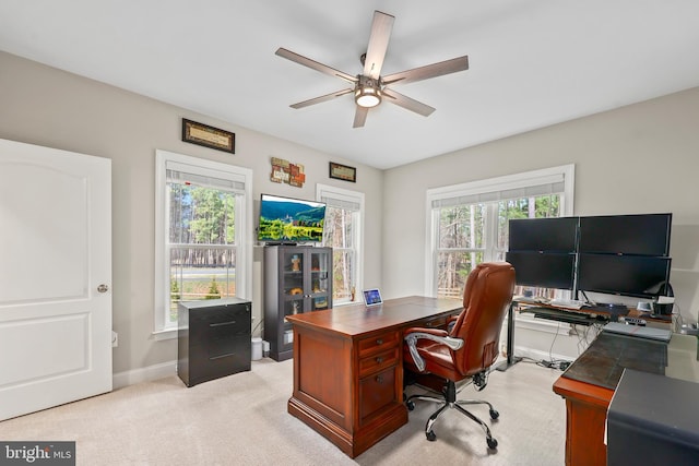 home office featuring light colored carpet, baseboards, and a ceiling fan