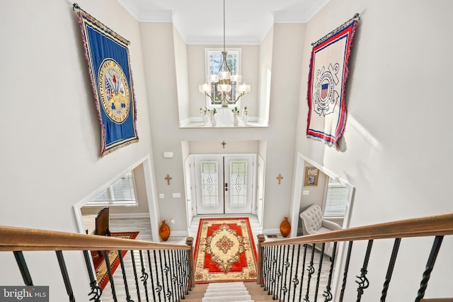 foyer with stairway, wood finished floors, a high ceiling, ornamental molding, and a notable chandelier