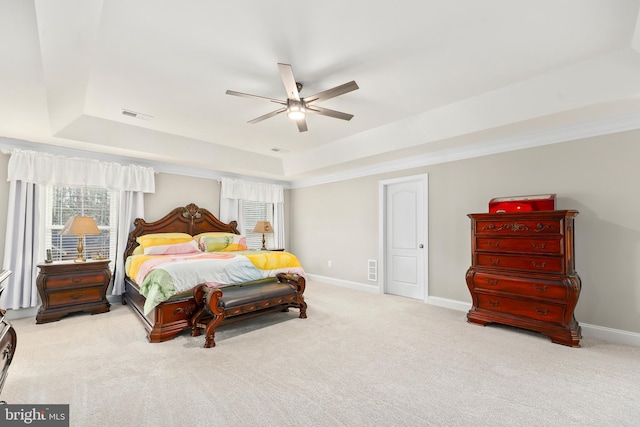 bedroom with visible vents, baseboards, carpet floors, a tray ceiling, and ceiling fan