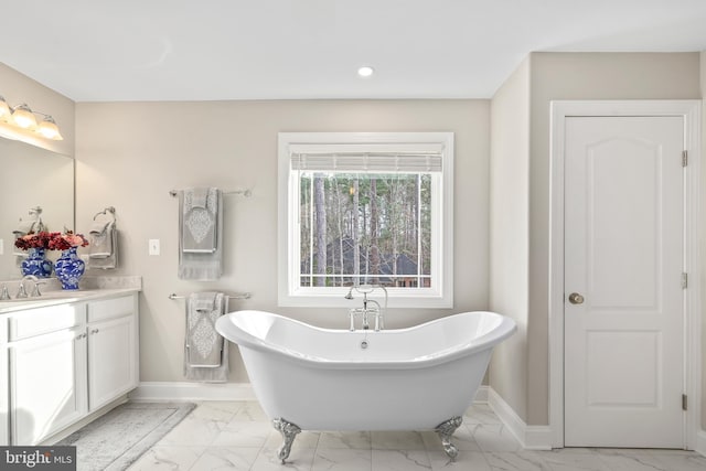 bathroom with vanity, baseboards, a freestanding tub, recessed lighting, and marble finish floor