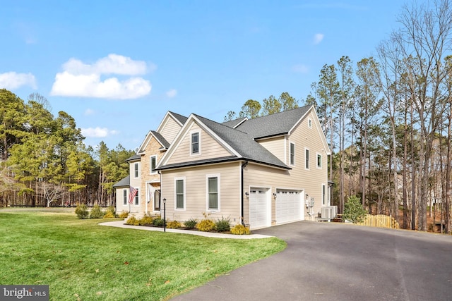 view of front facade with a front lawn, roof with shingles, central AC unit, a garage, and driveway