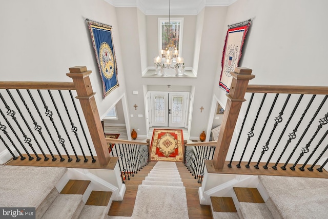 entryway featuring crown molding, stairway, a high ceiling, an inviting chandelier, and wood finished floors