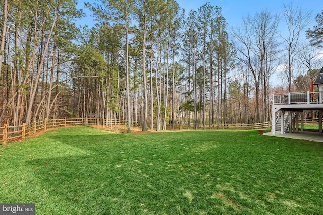 view of yard featuring a deck, stairway, and a fenced backyard