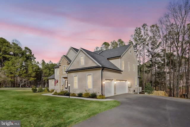 view of front of property featuring aphalt driveway, a front yard, central AC, and an attached garage