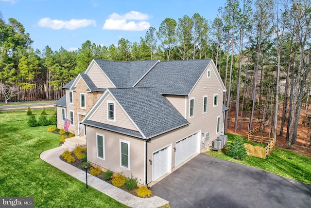 view of front of property with aphalt driveway, central AC, a front lawn, and roof with shingles