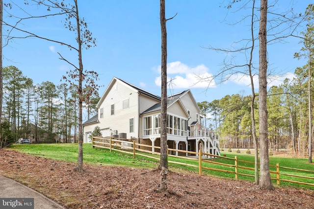 view of home's exterior with a lawn, fence, stairs, and a sunroom