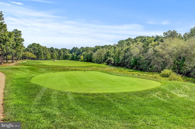 view of property's community featuring view of golf course and a yard