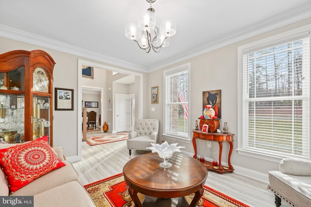 living area featuring light wood-style flooring, baseboards, crown molding, and an inviting chandelier