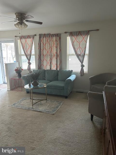 living area featuring a ceiling fan and carpet flooring