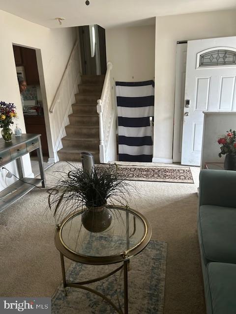 living area featuring light carpet and stairs