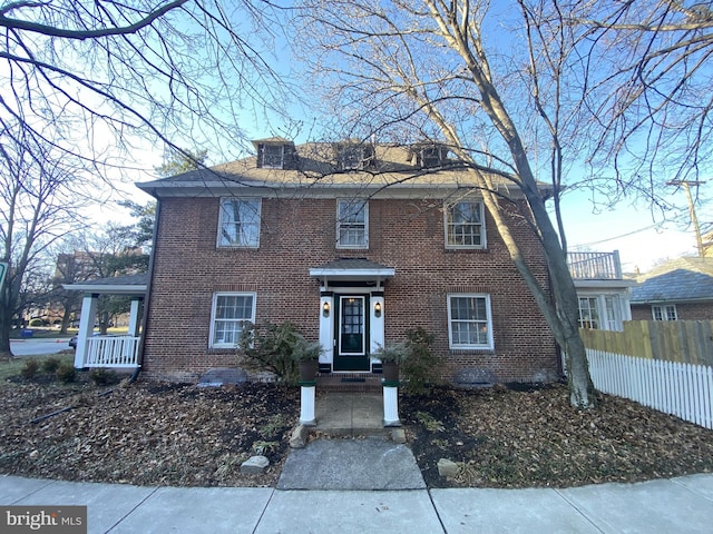 view of front facade featuring brick siding and fence