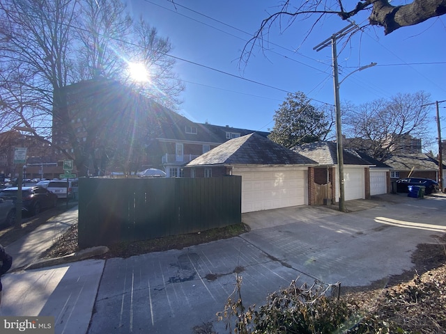 view of side of property with a garage, brick siding, fence, and driveway