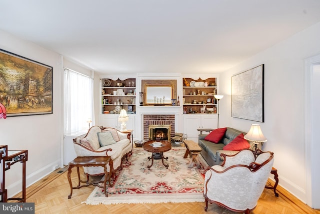 living area featuring a brick fireplace and baseboards