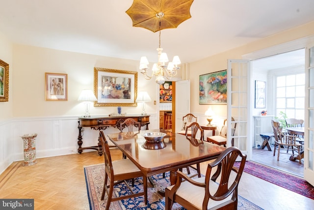 dining room with a decorative wall, wainscoting, and a notable chandelier