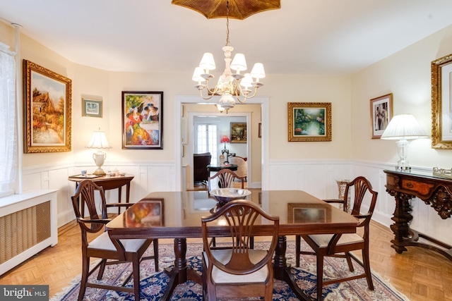 dining space with radiator, an inviting chandelier, and wainscoting