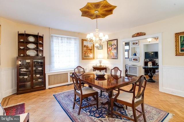 dining room with a chandelier, wainscoting, and radiator heating unit