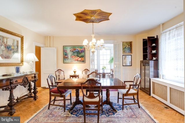 dining space featuring wainscoting, radiator heating unit, and an inviting chandelier