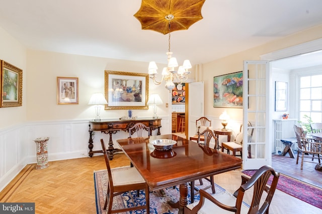 dining room featuring wainscoting, a notable chandelier, and a decorative wall