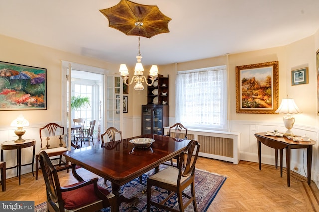 dining area featuring radiator, a chandelier, and wainscoting