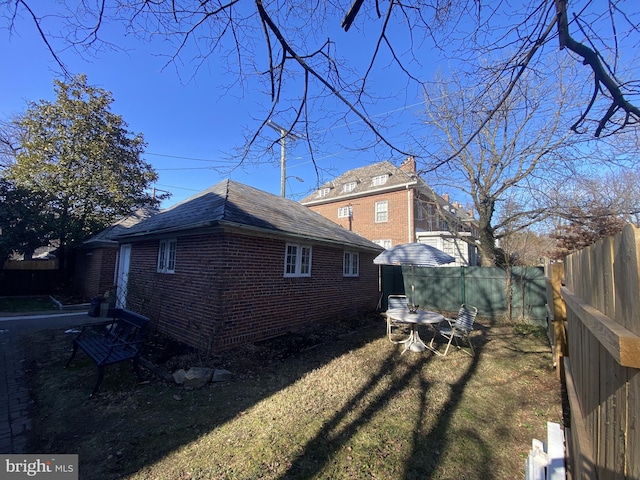 view of side of property featuring brick siding, a lawn, and a fenced backyard