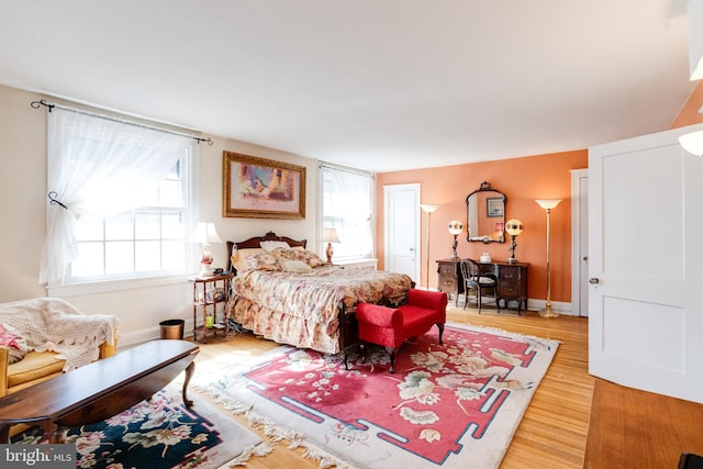 bedroom featuring light wood-style floors, multiple windows, and baseboards