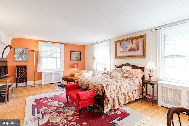 bedroom featuring radiator, multiple windows, and wood finished floors