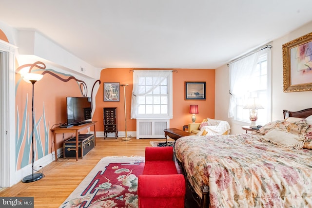 bedroom with radiator, baseboards, and wood finished floors