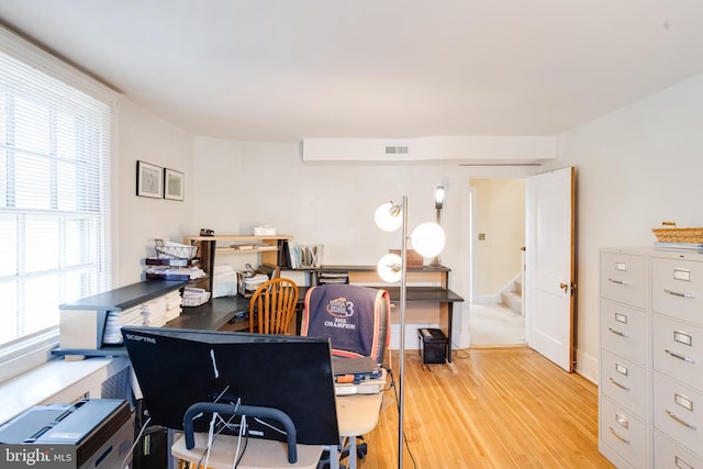 home office with light wood-style floors and visible vents