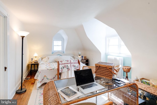 bedroom featuring radiator, hardwood / wood-style flooring, baseboards, and vaulted ceiling