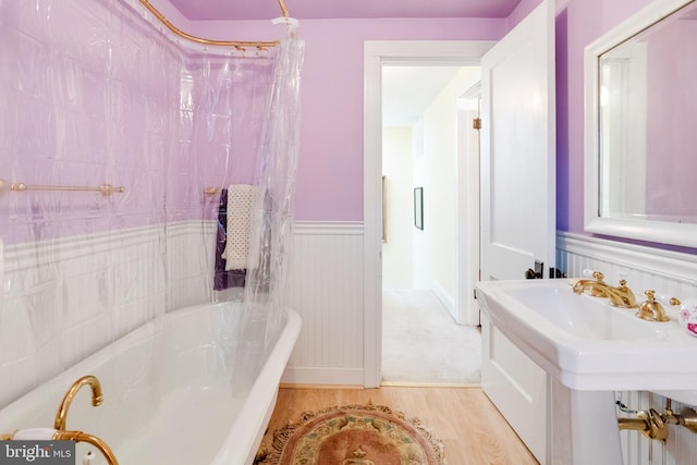 full bath with a wainscoted wall and wood finished floors