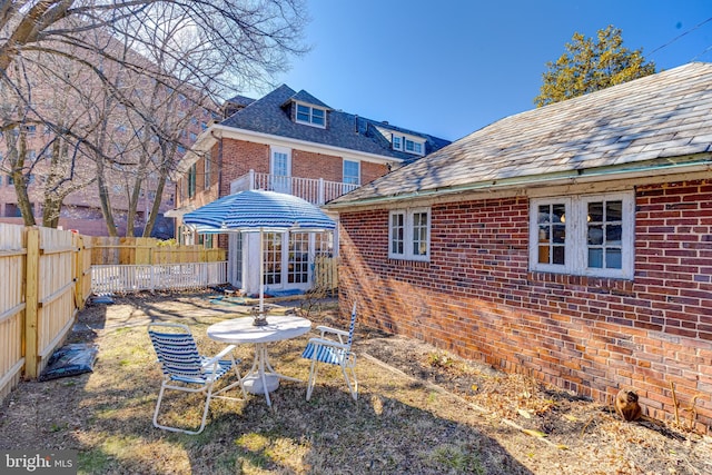 back of house featuring a fenced backyard and brick siding