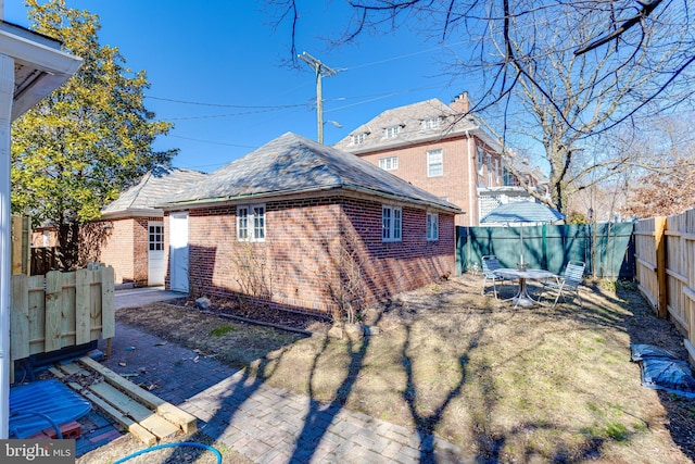 view of side of home with brick siding, a patio area, and a fenced backyard