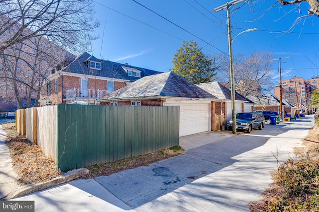 view of property exterior with a high end roof, a detached garage, and brick siding