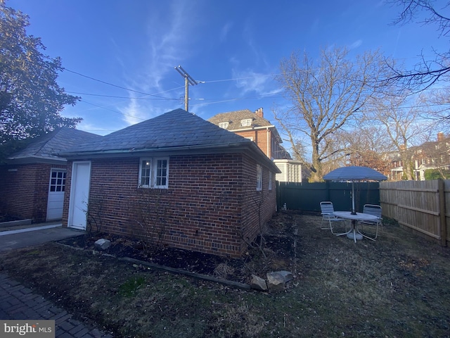 view of side of property with brick siding and a fenced backyard