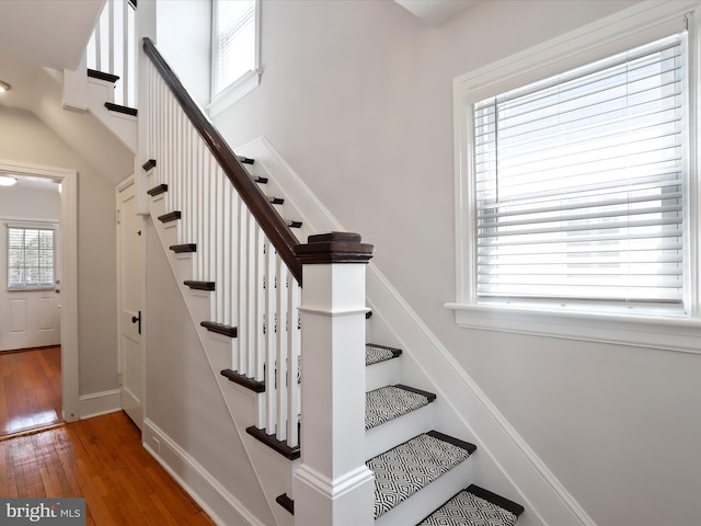 staircase with a high ceiling, baseboards, and hardwood / wood-style flooring