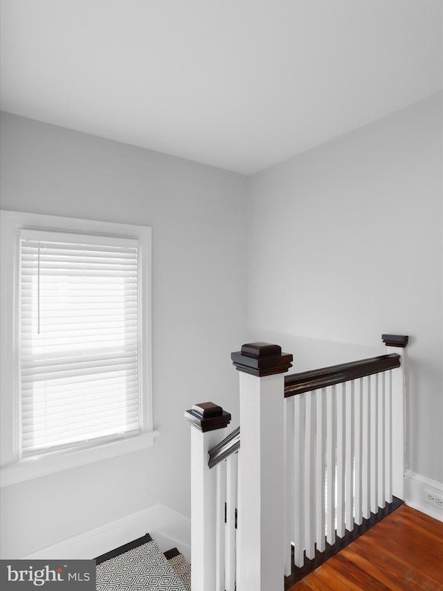 staircase featuring wood finished floors and baseboards