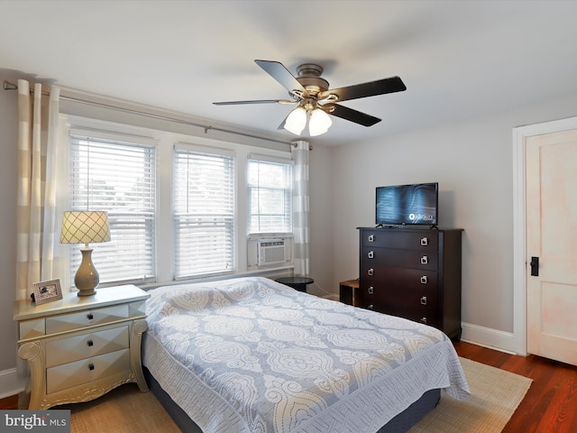 bedroom featuring a ceiling fan, cooling unit, baseboards, and wood finished floors