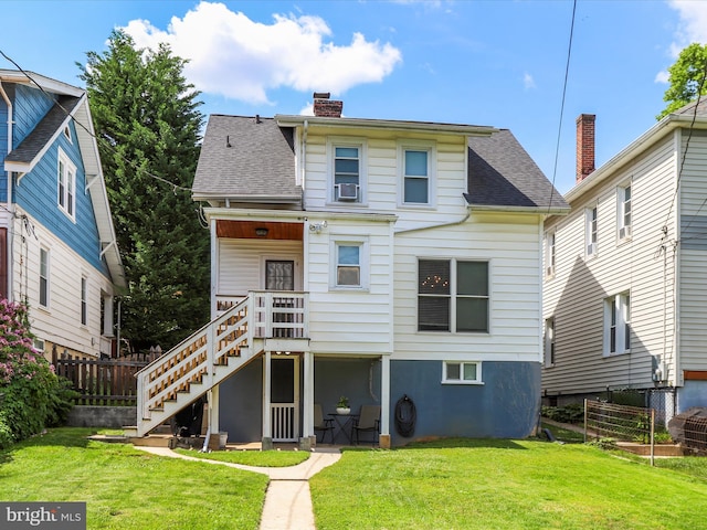 back of house with roof with shingles, a yard, a chimney, stairway, and fence